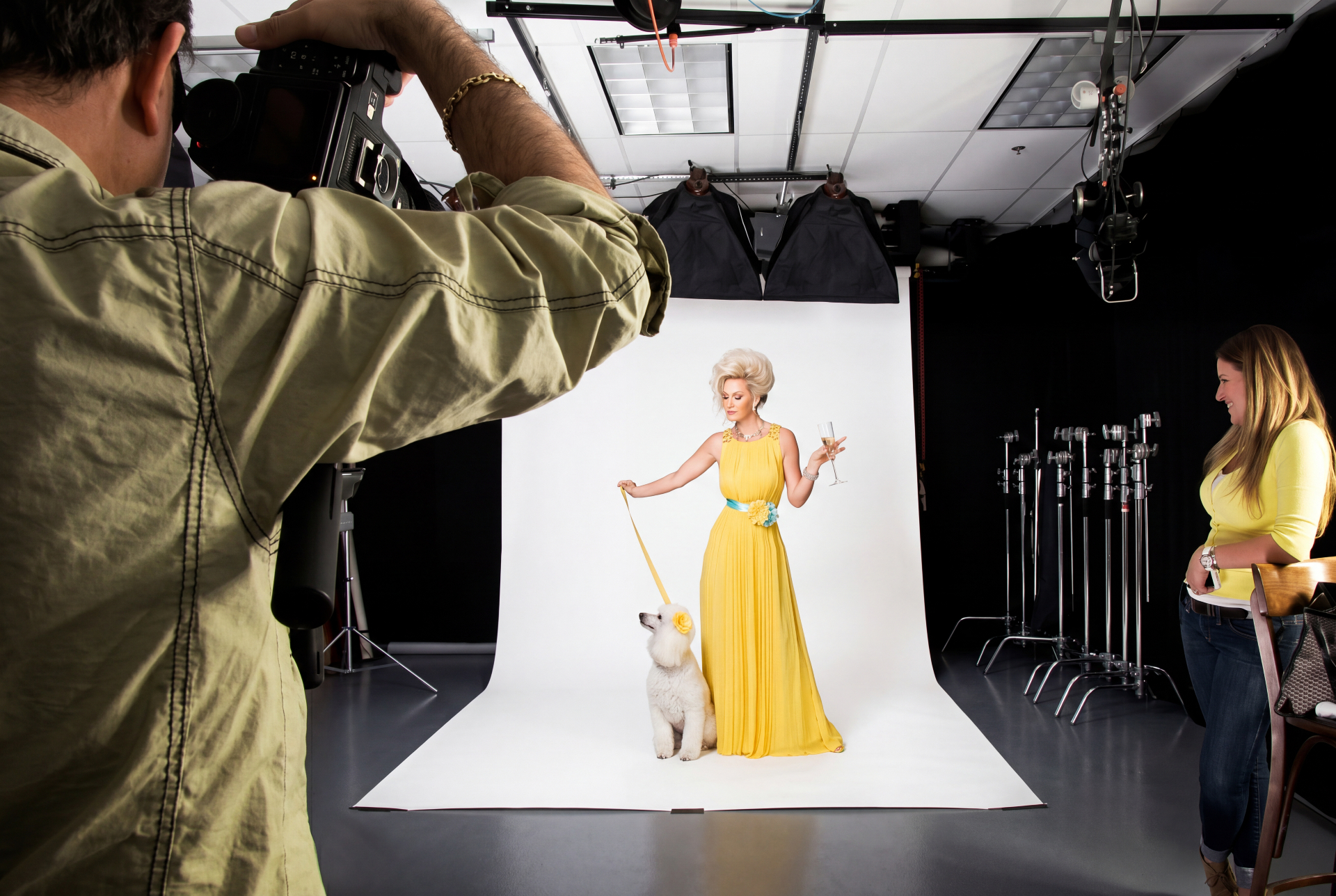 Michael Lloyd photographing a model in a yellow dress with a white poodle inside Lloyd's Studio in Boca Raton.