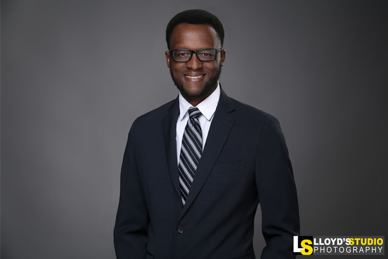 Professional business headshot of a smiling man in a navy suit and striped tie, photographed by Lloyd's Studio in Boca Raton